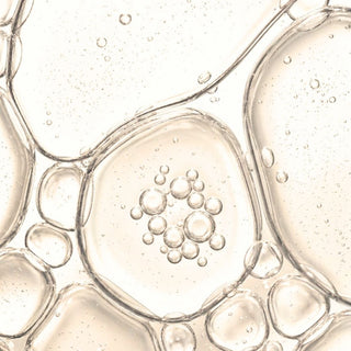 A close-up abstract view of transparent bubble-like droplets in a pale warm beige background.