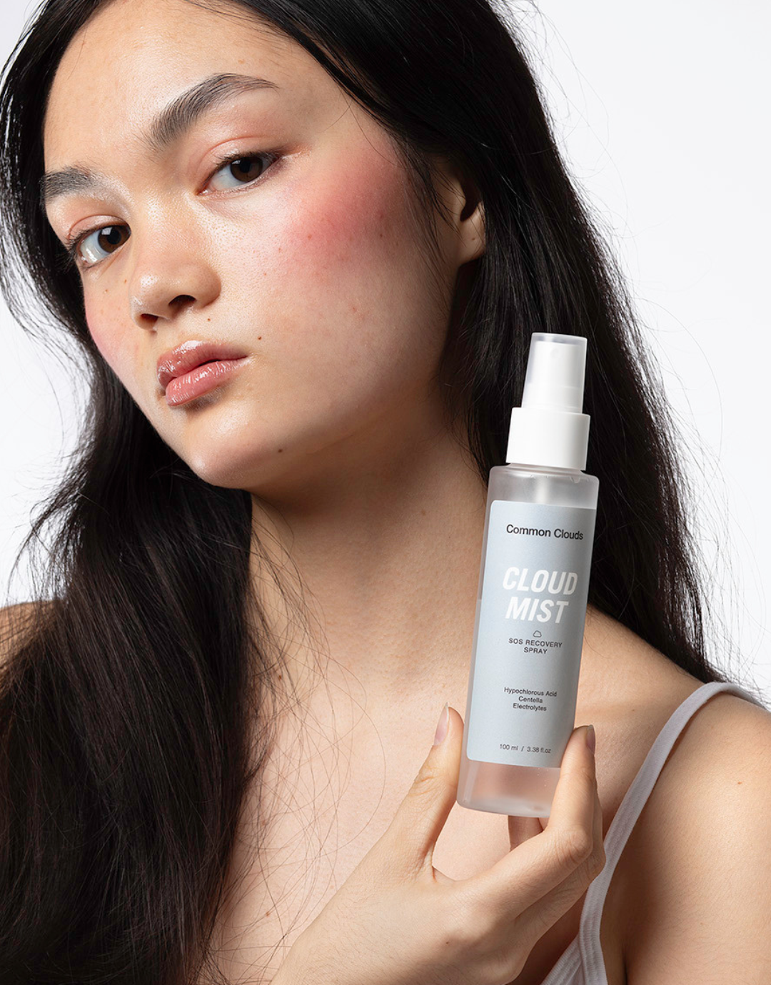 Girl holding a super soothing SOS recovery spray next to her face.