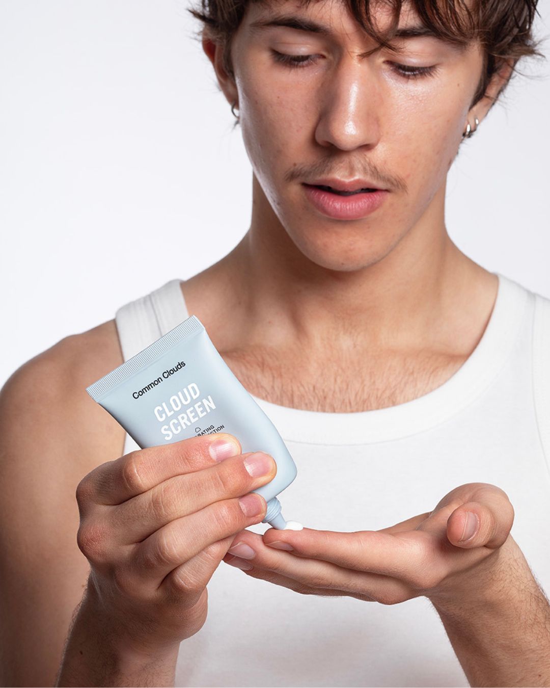A man holding Cloud Screen sunscreen, perfect for acne-prone and sensitive skin, offering high UV protection and hydration.