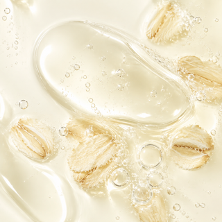Close-up of a clear, glossy liquid with visible oatmeal flakes and small bubbles, suggesting a skincare or cosmetic ingredient texture shot.