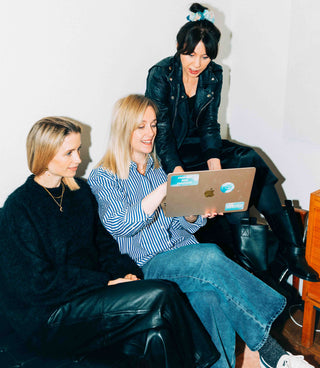 3 female founders from Common Clouds sitting on a sofa looking at at a computer screen. 