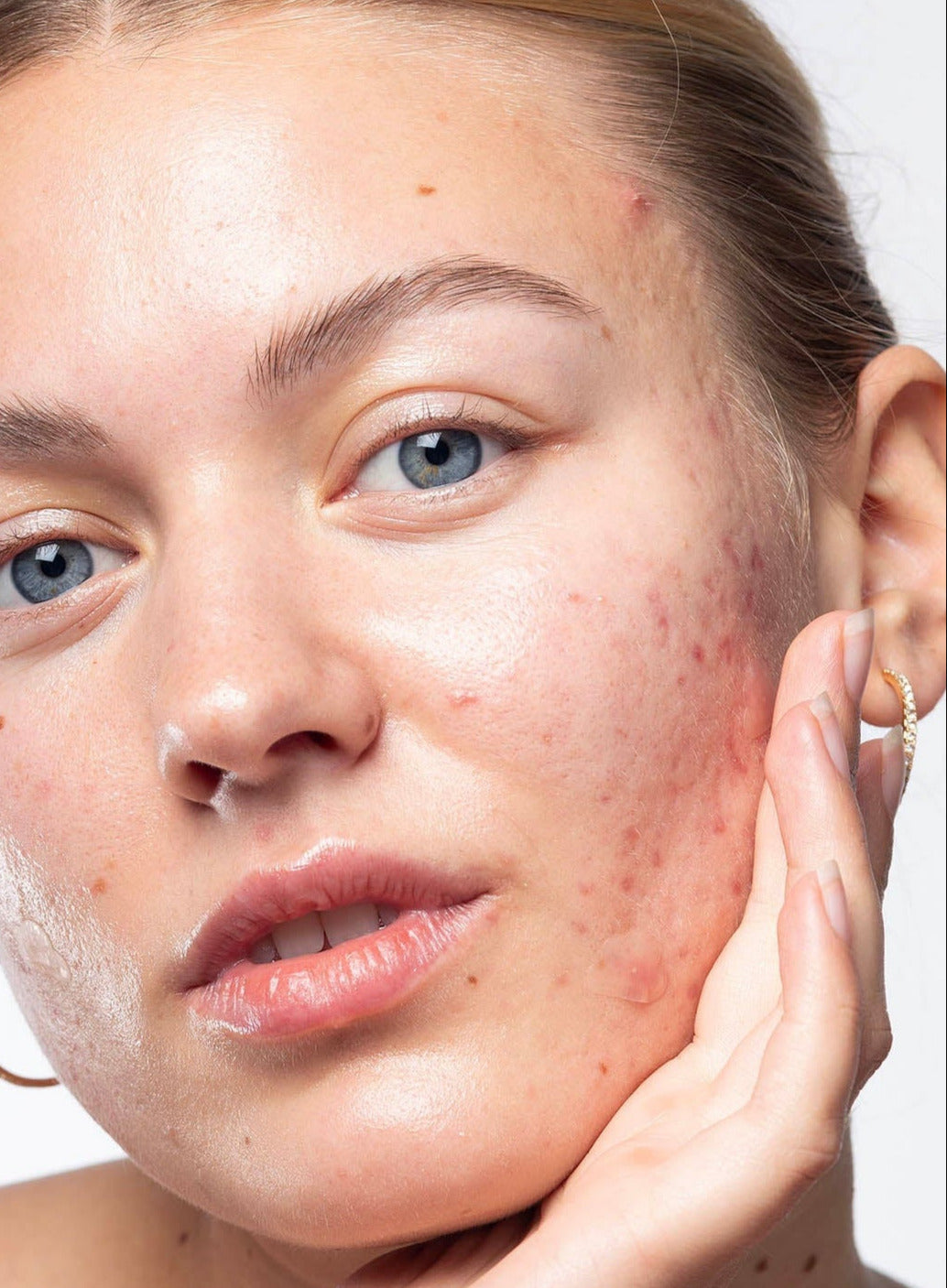 Woman holding a skincare product with a plain background