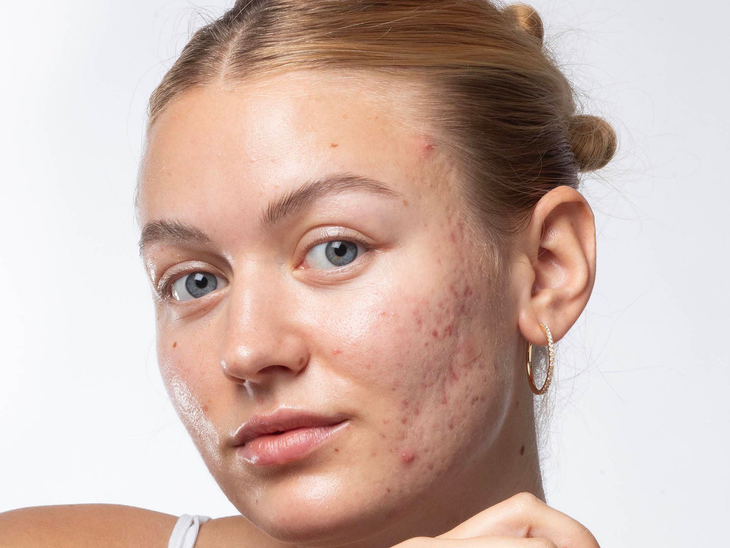 Woman holding a skincare product with a plain background