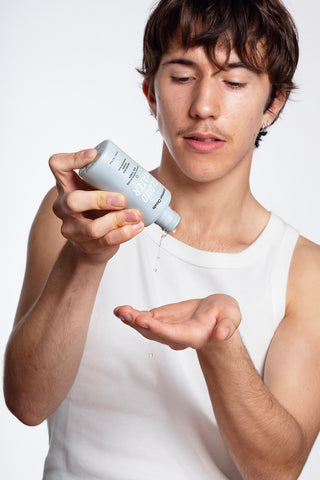 A boy showing how to apply CLOUD WATER BHA-toner from Common Clouds to his face by pouring some in his hand.