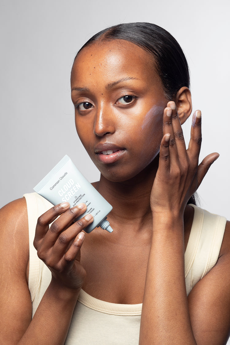 Woman applying skincare product to her face with a neutral background