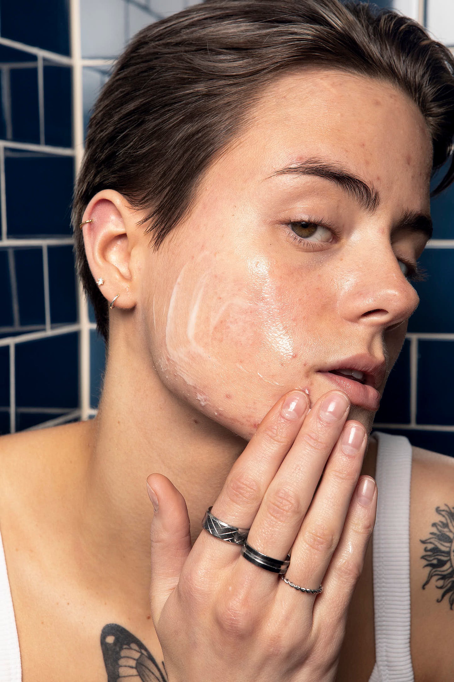 Girl applying a redness relief serum on her cheek.