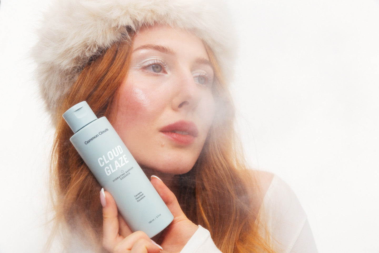 Woman holding a bottle of 'Cloud Glaze' product with a white background