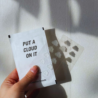 Hand holding Common Clouds Cloud Patch packaging with visible cloud-shaped pimple patches in natural light