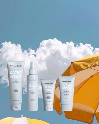 Set of Common Clouds skincare products with a beach umbrella and blue sky background