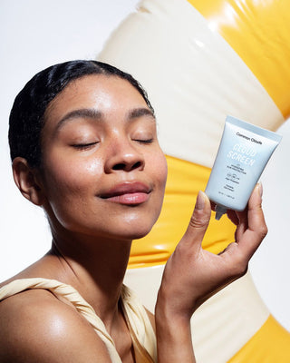 Woman with closed eyes holding Cloud Screen sunscreen tube, glowing with radiant skin. SPF50, ideal for acne-prone and sensitive skin.